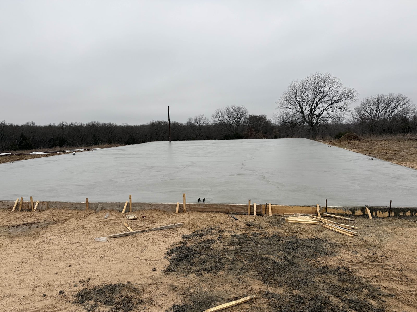 A large concrete building slab poured and finished, forms still set.