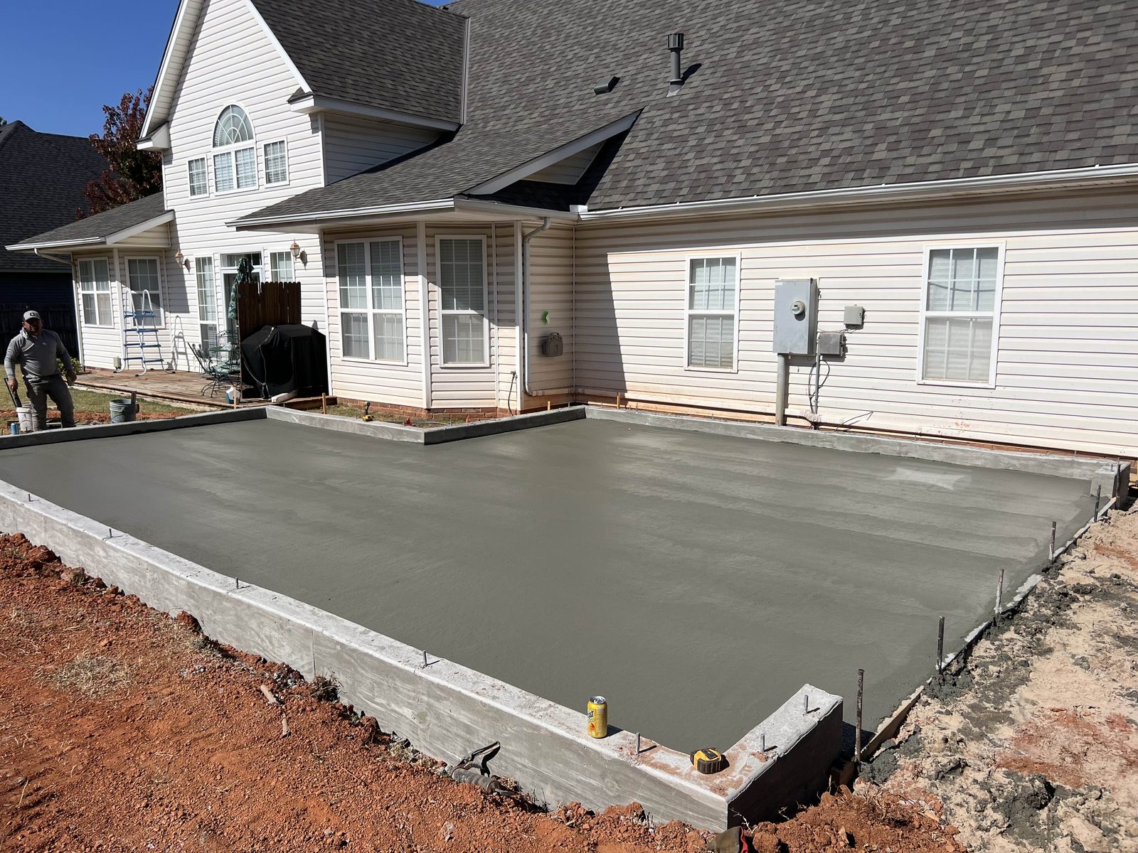 A concrete patio poured and floated out behind a house.